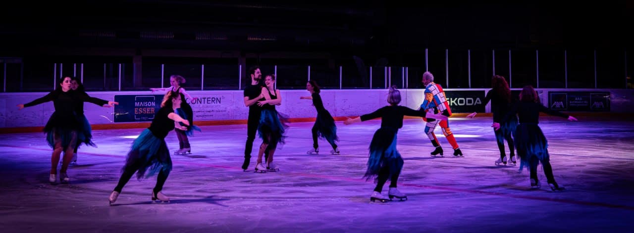 Groupe de patineurs lors d’un spectacle sur glace sous un éclairage violet